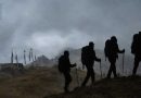 Fog‑covered mountain ridge at Tumling with silhouetted trekkers and prayer flags, reflecting the travel story by Srijit Das.