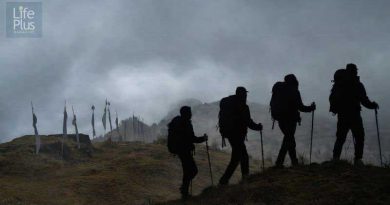 Fog‑covered mountain ridge at Tumling with silhouetted trekkers and prayer flags, reflecting the travel story by Srijit Das.